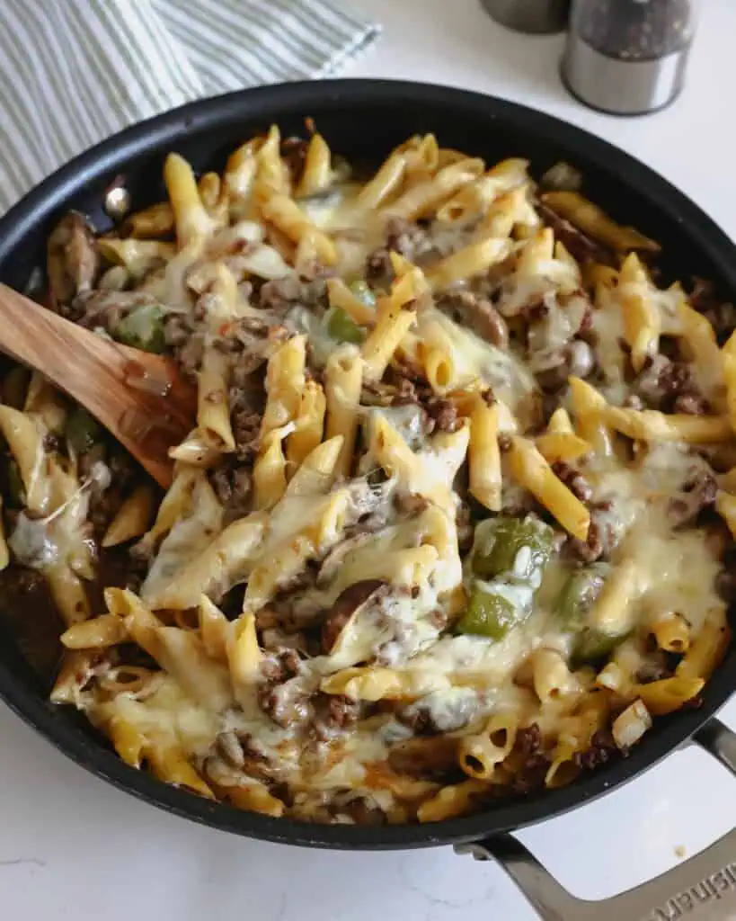 An overhead view of philly cheesesteak  pasta in a skillet. 