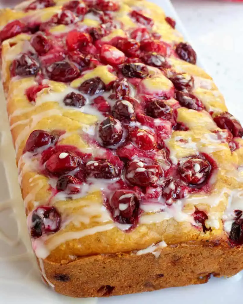 A close up view of cranberry orange bread on a serving platter. 