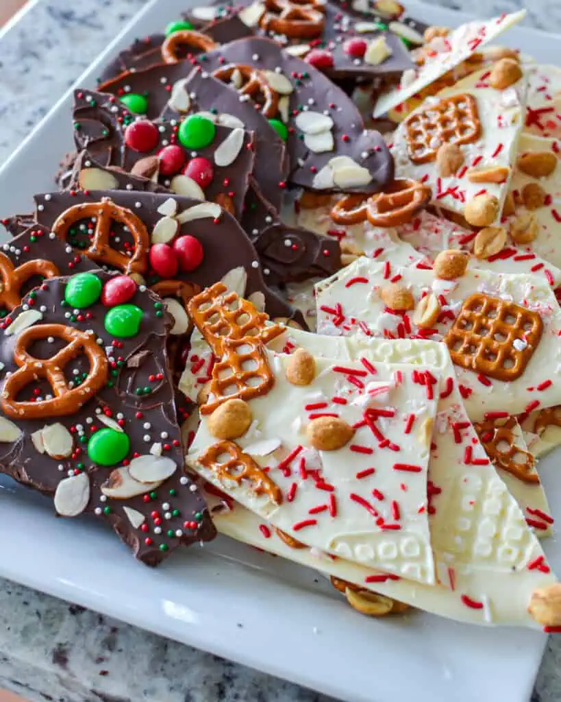 A platter with dark chocolate Christmas bark down one side and white choolate Christmas bark down the other side. 