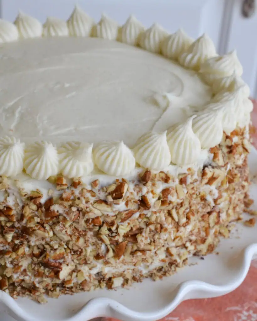 The over head view of carrot cake cake with cream cheese frosting, a piped edges and chopped pecans down the side. 