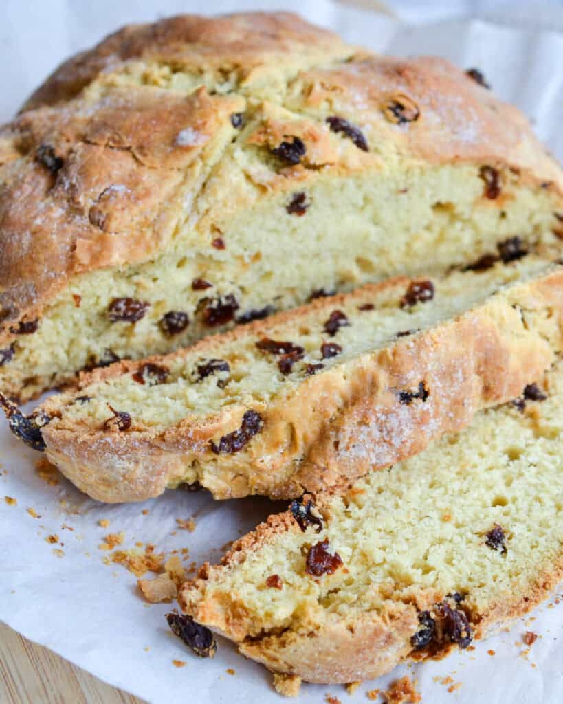 Sliced soda bread on a parchment paper covered cutting board. 