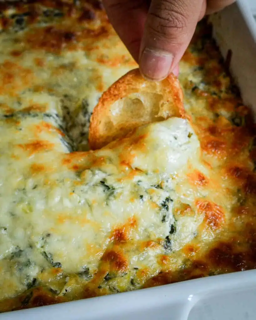 A crostini dipped in spinach artichoke dip. 