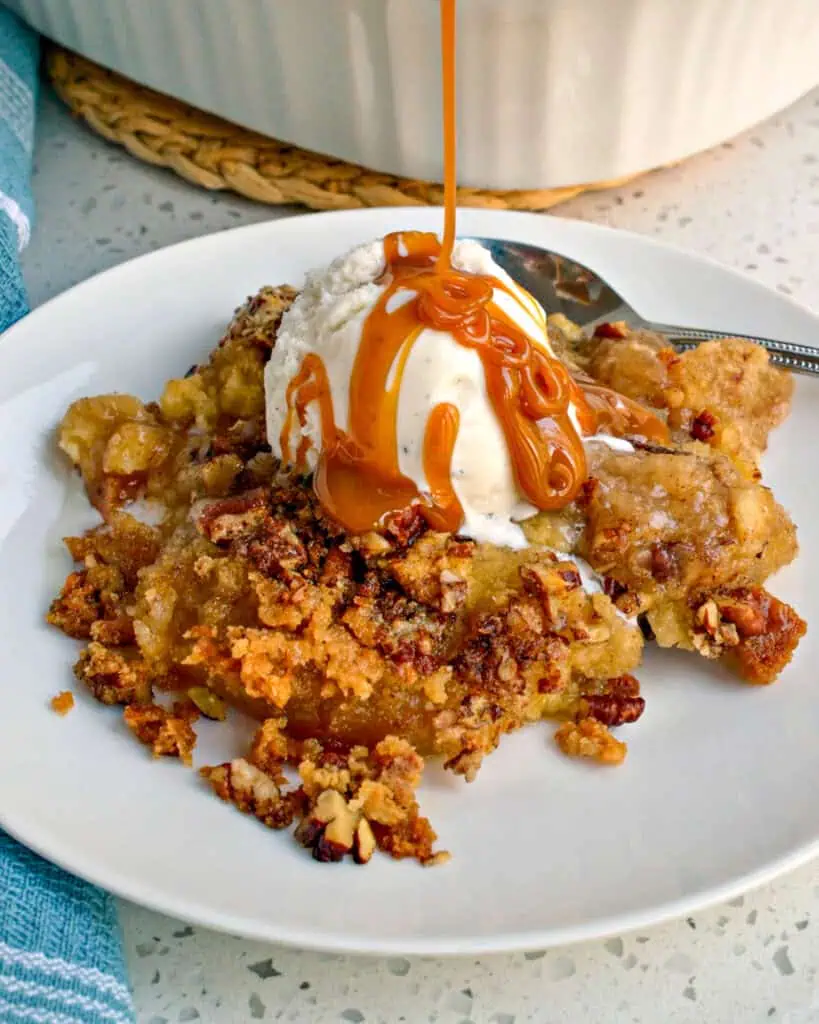 Apple Dump cake on a single plate a la mode and drizzled with caramel sauce. 