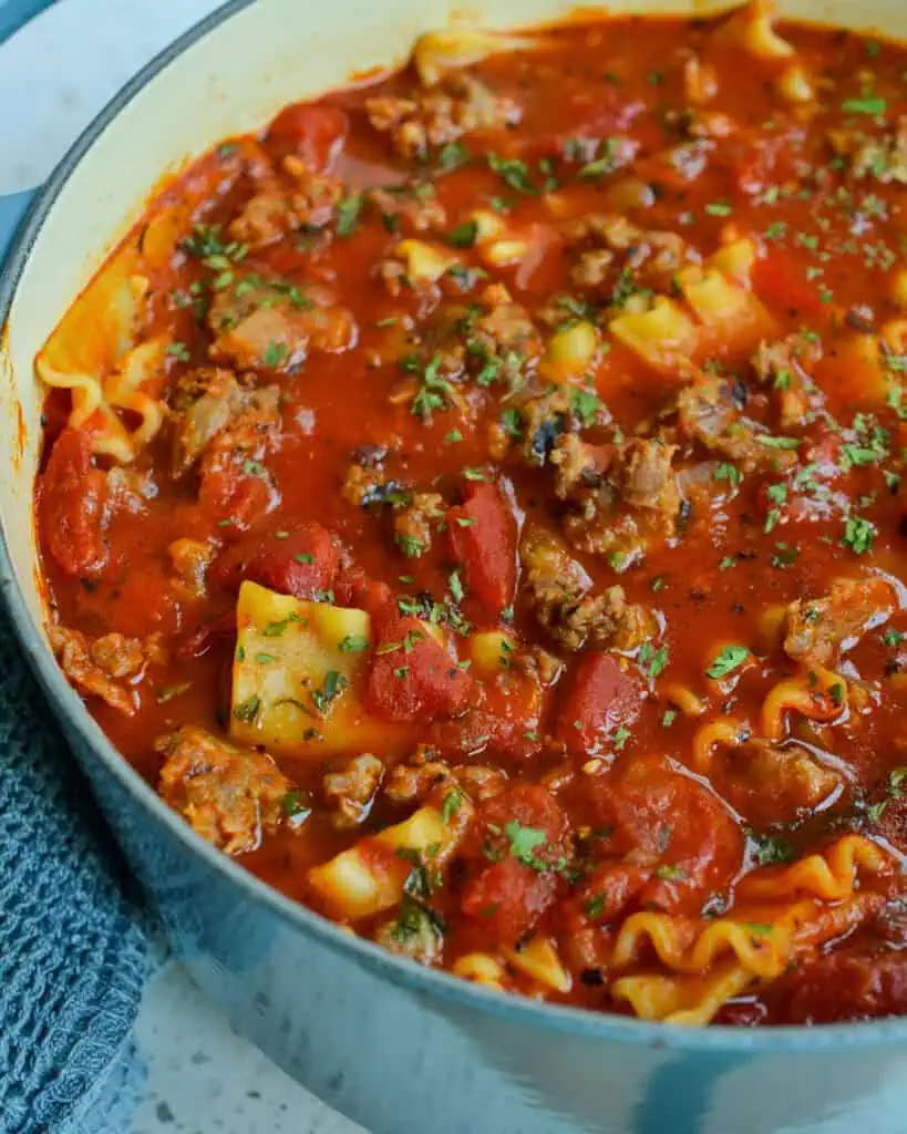 A Dutch oven full of lasagna soup with Italian Sausage, crushed tomatoes, lasagna noodles and a perfect blend of spice. 