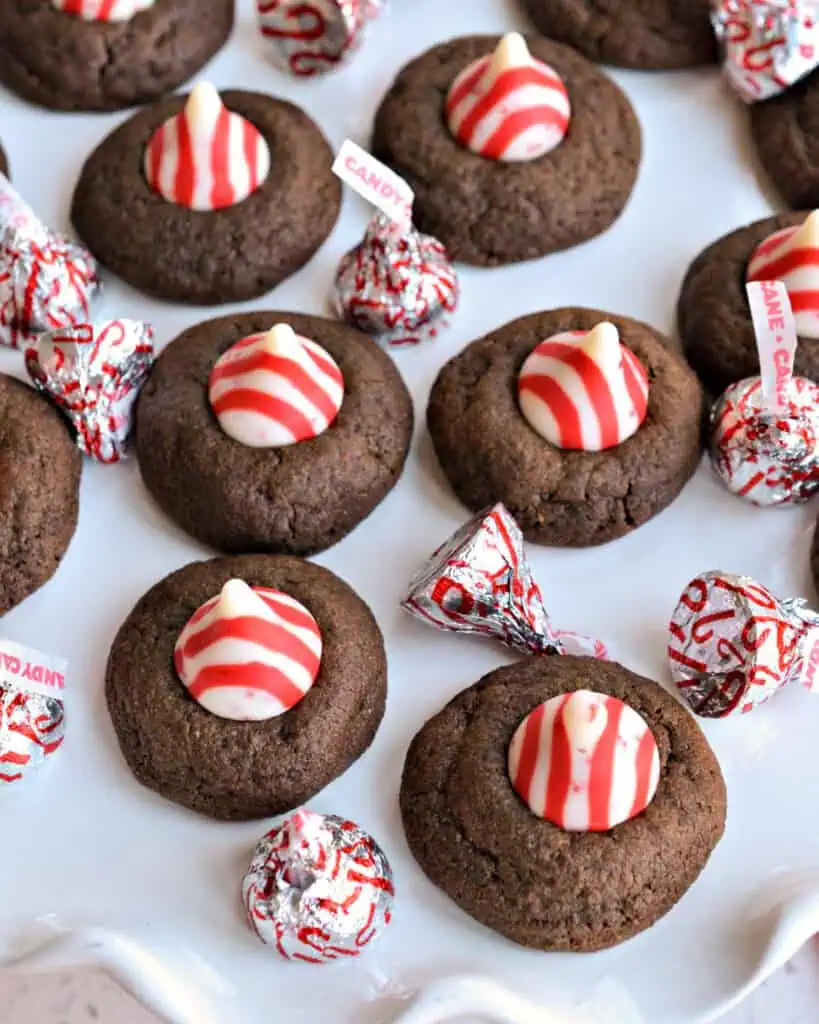 Chocolate Peppermint Thumbprint Cookies on a cake plate with peppermint kisses. 