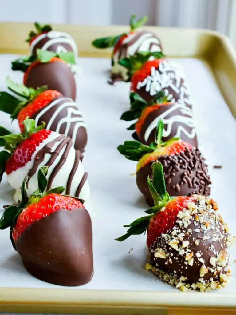 Chocolate covered strawberries on a parchment covered baking sheet. 