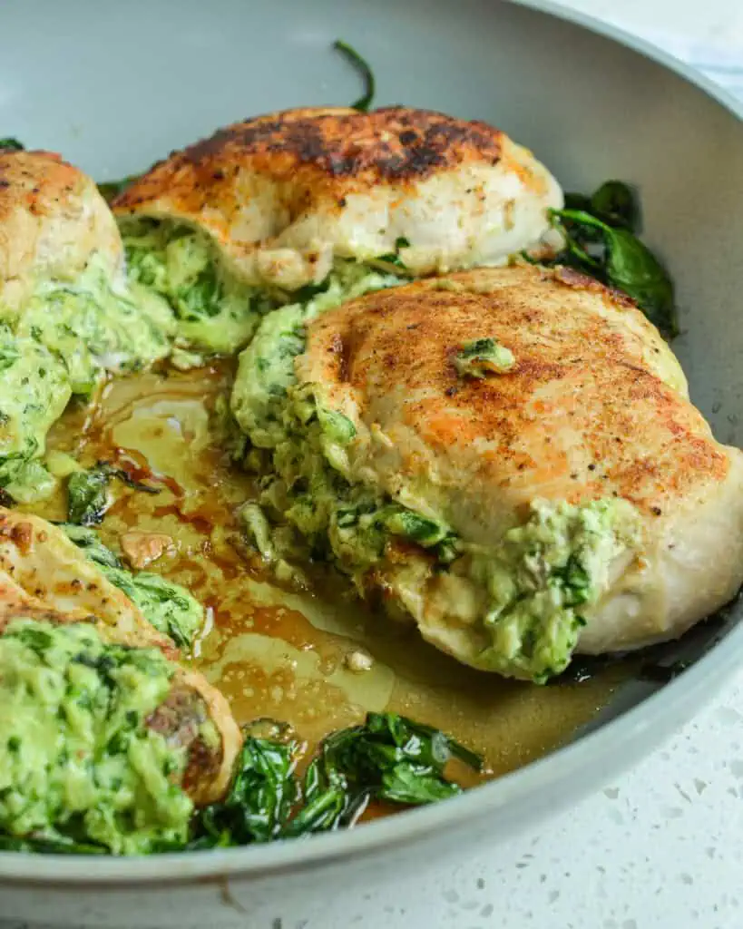 Spinach stuffed chicken breasts in a large gray skillet. 