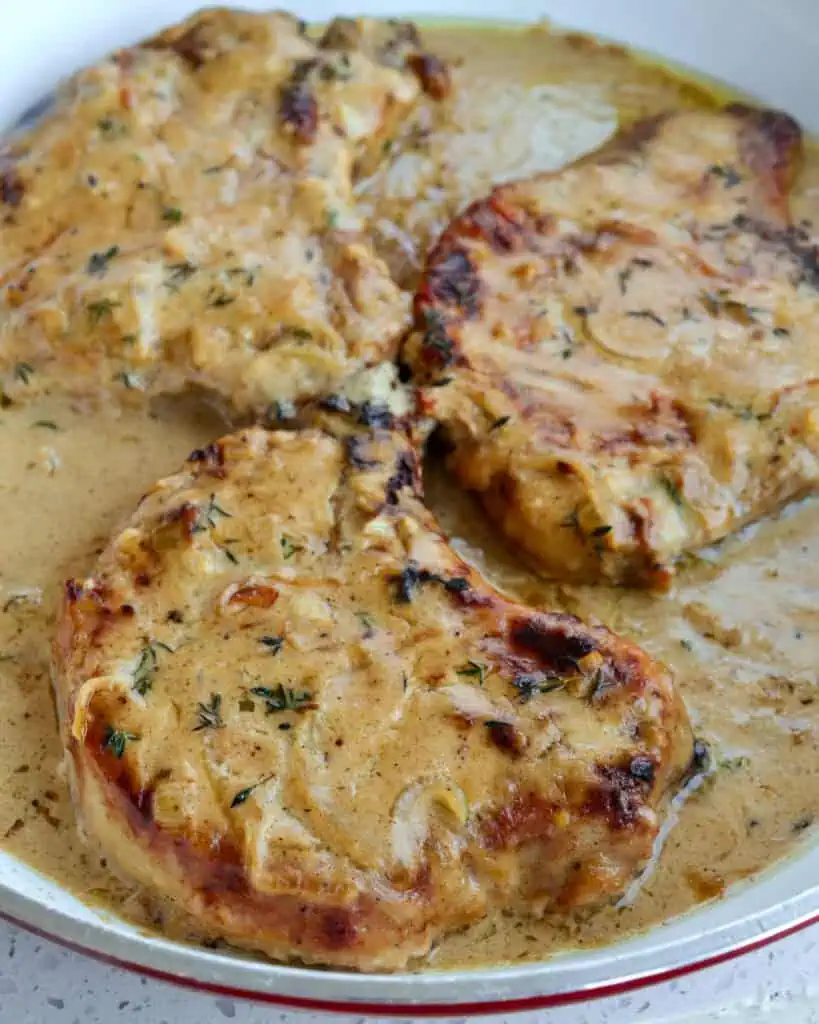 Fried pork chops with smothereed gravy in a large skillet. 