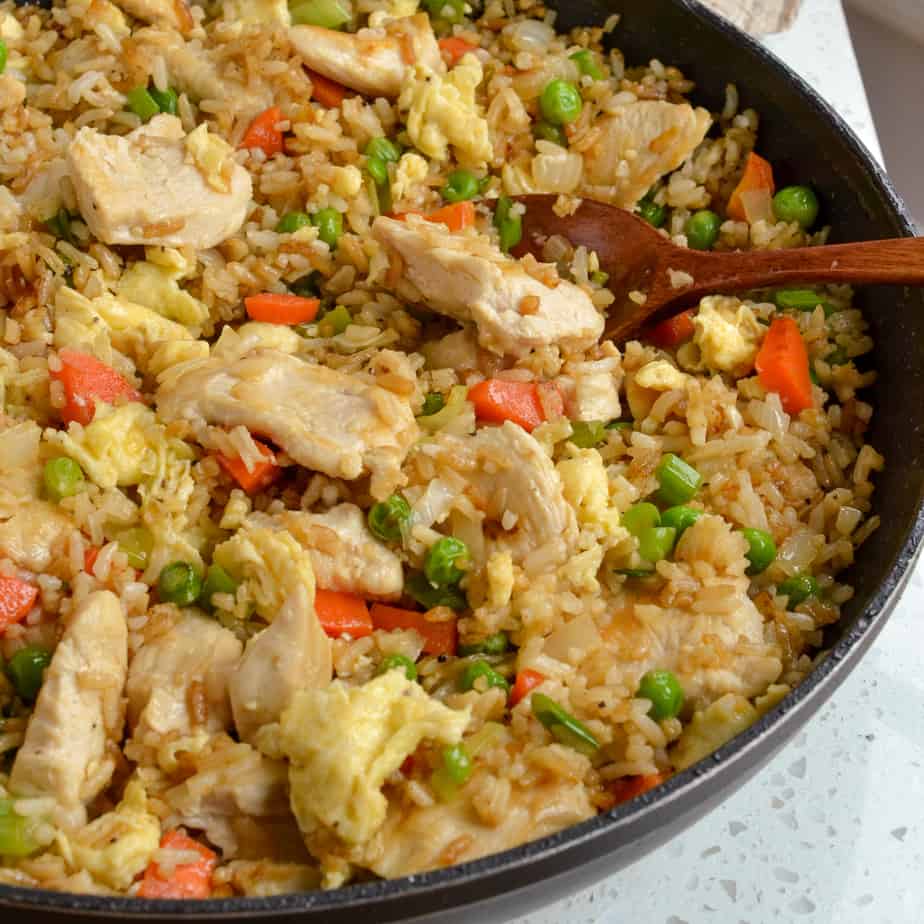 Peas, carrots, eggs, and chicken in skillet fried rice. 