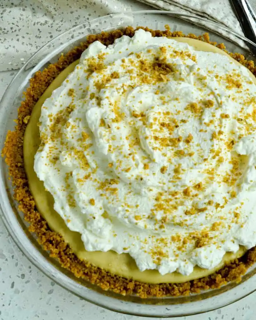 A whole butterscotch pie topped with whipped cream. 