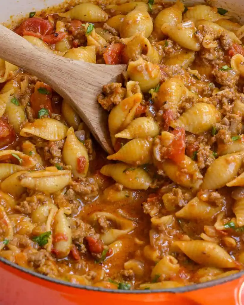 A close up view of taco pasta with onions, garlic, tomatoes, cheddar, and Monterey Jack Cheese