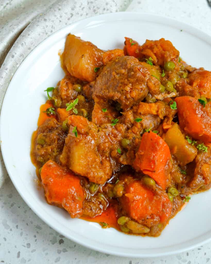 A serving plate full of pork stew with a fork on the side. 