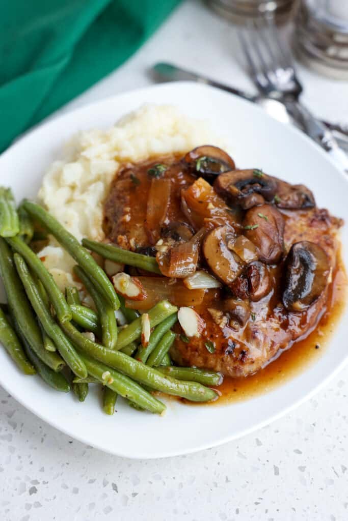 Cube steak smothered in gravy over mashed potatoes with a side of green beans. 