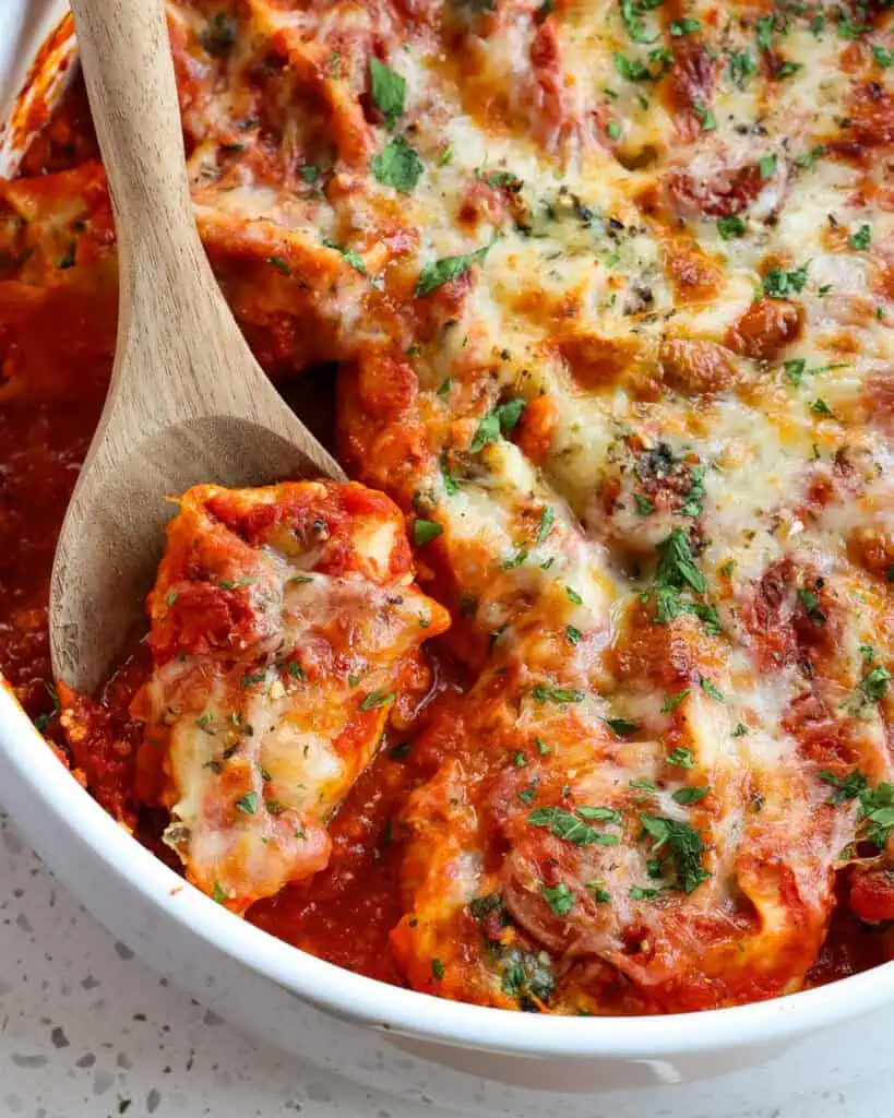 A round casserole dish full of ricotta and spinach stuffed shells. 