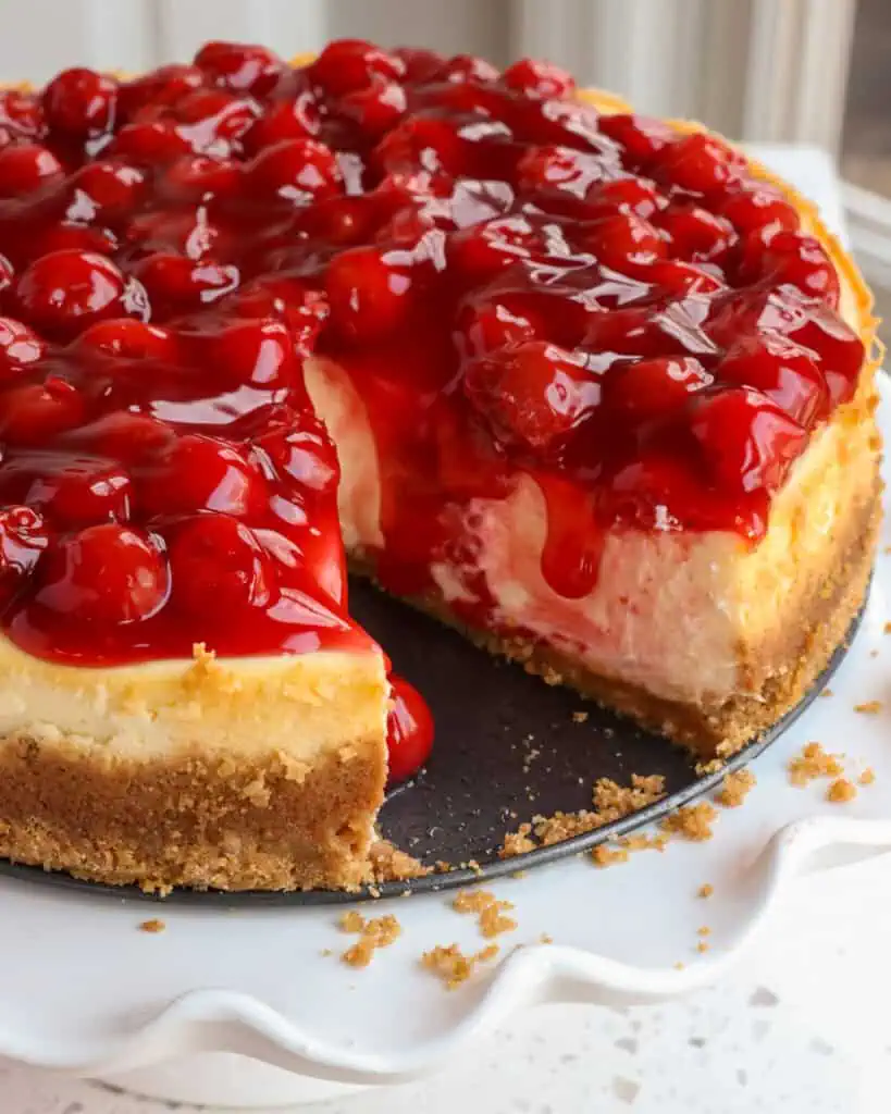 Homemade cheesecake with cherry pie filling and slice cut out. 