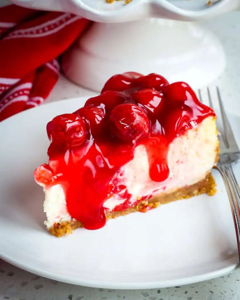 A piece of cherry cheesecake on a plate with a fork. 