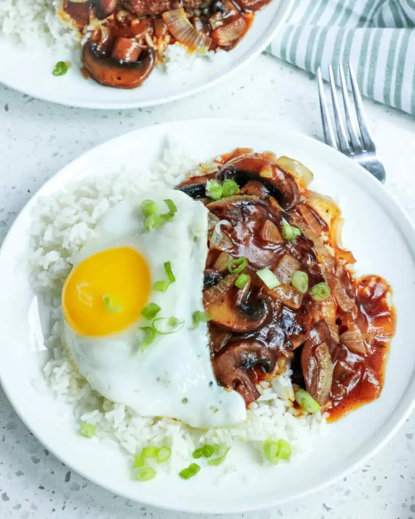 This Hawaiian Loco Moco recipe is pan fried hamburger patties over white rice smothered with a mushroom onion brown gravy and a sunny side up fried egg. 