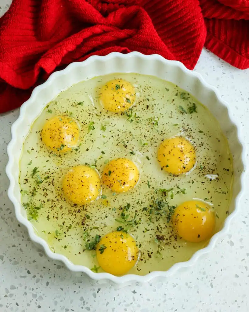 Crack the eggs in the dish and sprinkle with about 1 tablespoon of fresh herbs like thyme, rosemary, and Italian parsley.