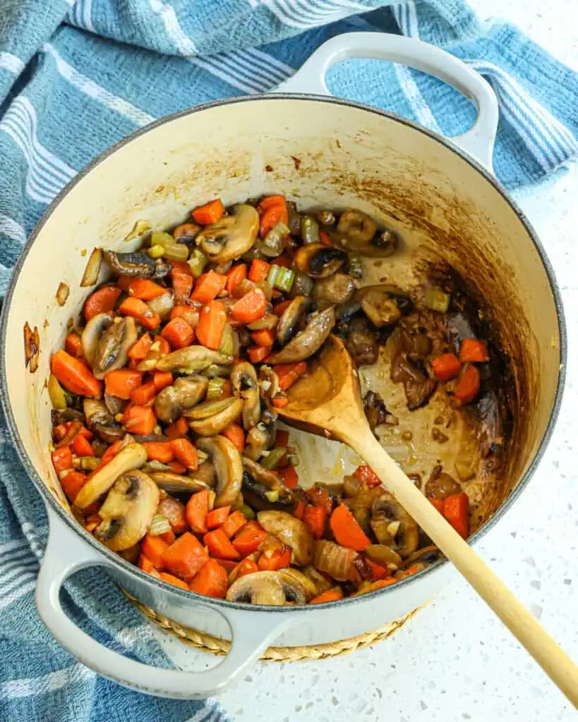 Add the onions, celery, and carrots, and cook until the onions and celery are soft and the carrots start to soften. Reduce the heat to low and add the garlic, cooking for one minute while stirring. 