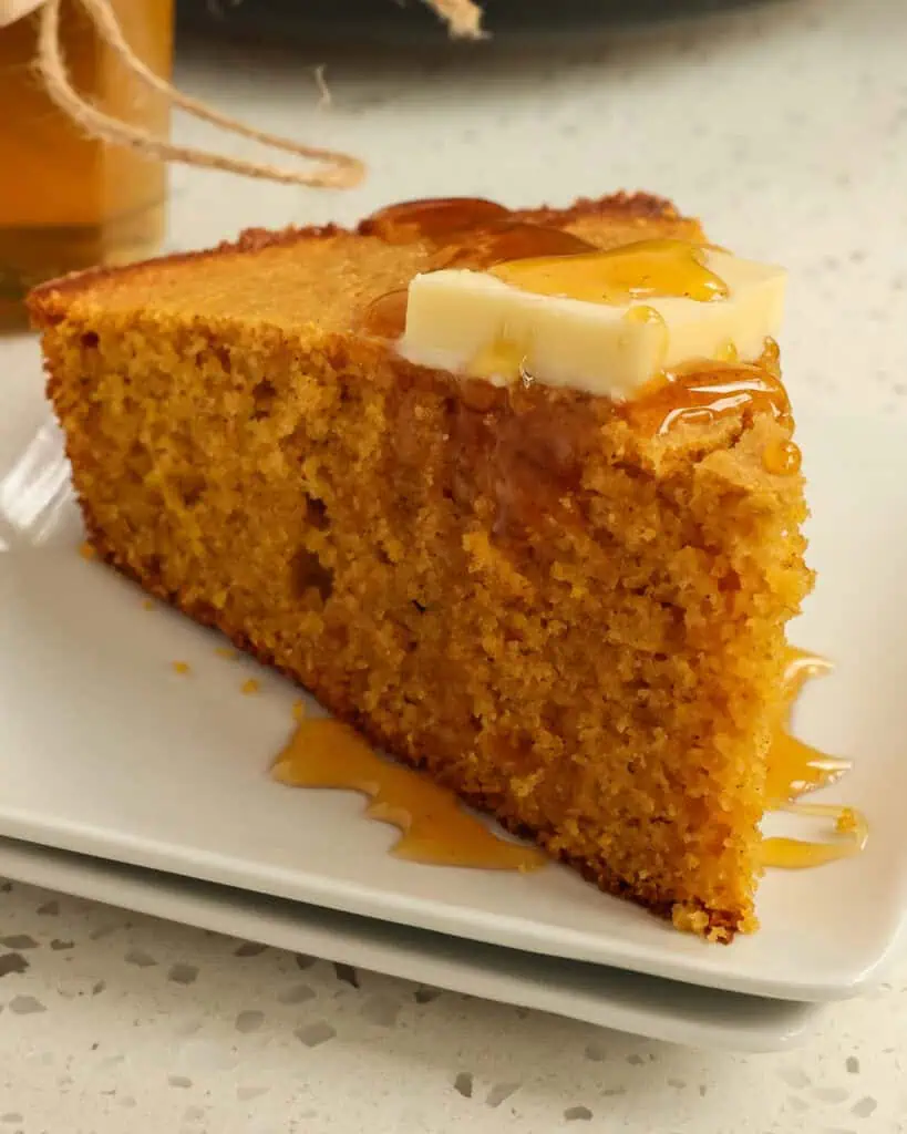 A closse up view of sweet potato bread with honey and butter on top. 
