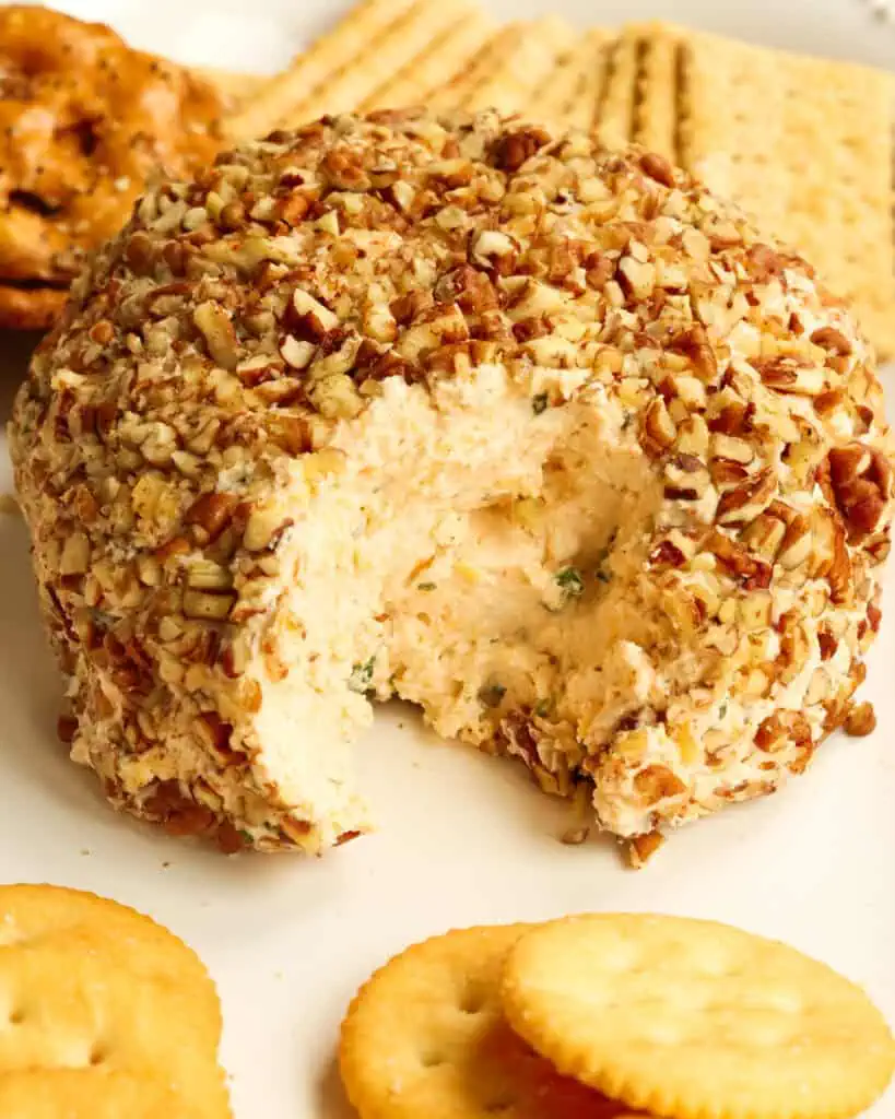 A classic cheese ball made with cream cheese, sharp cheddar cheese, green onions, and a few tasty spices, all combined and rolled in chopped pecans. 