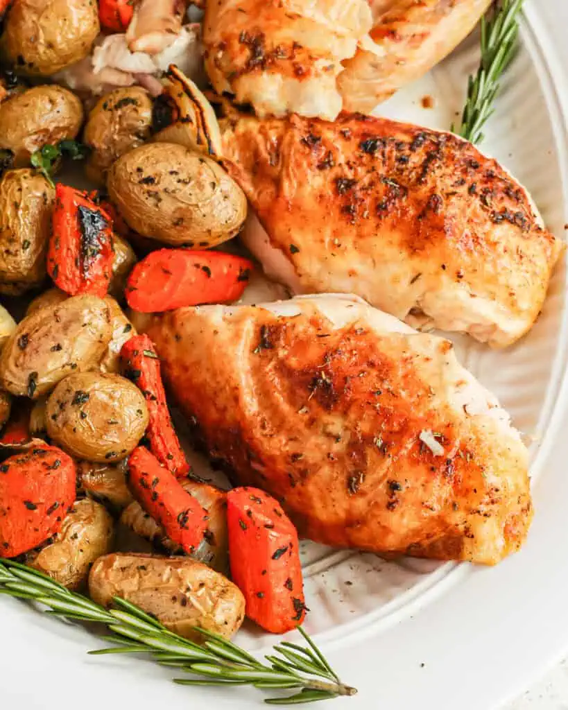 Roasted vegetables with roasted chicken on a large serving platter. 