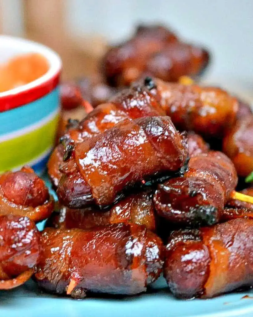 A small plate full of bacon wrapped little smokies basted in brown sugar. 