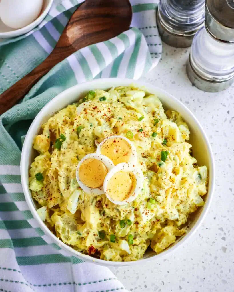 An overhead view of southern potato salad garnished with sliced eggs and paprika. 