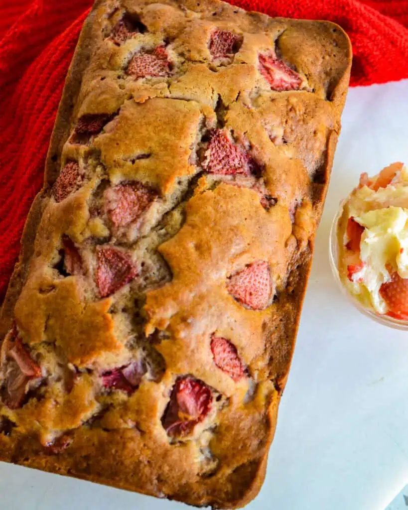 A loaf of homemade strawberry bread with a small dish of strawberry butter on the side. 