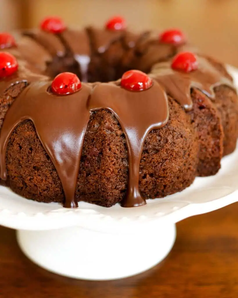 An overhead view of chocolate cherry cake on a whitle cake stand. 