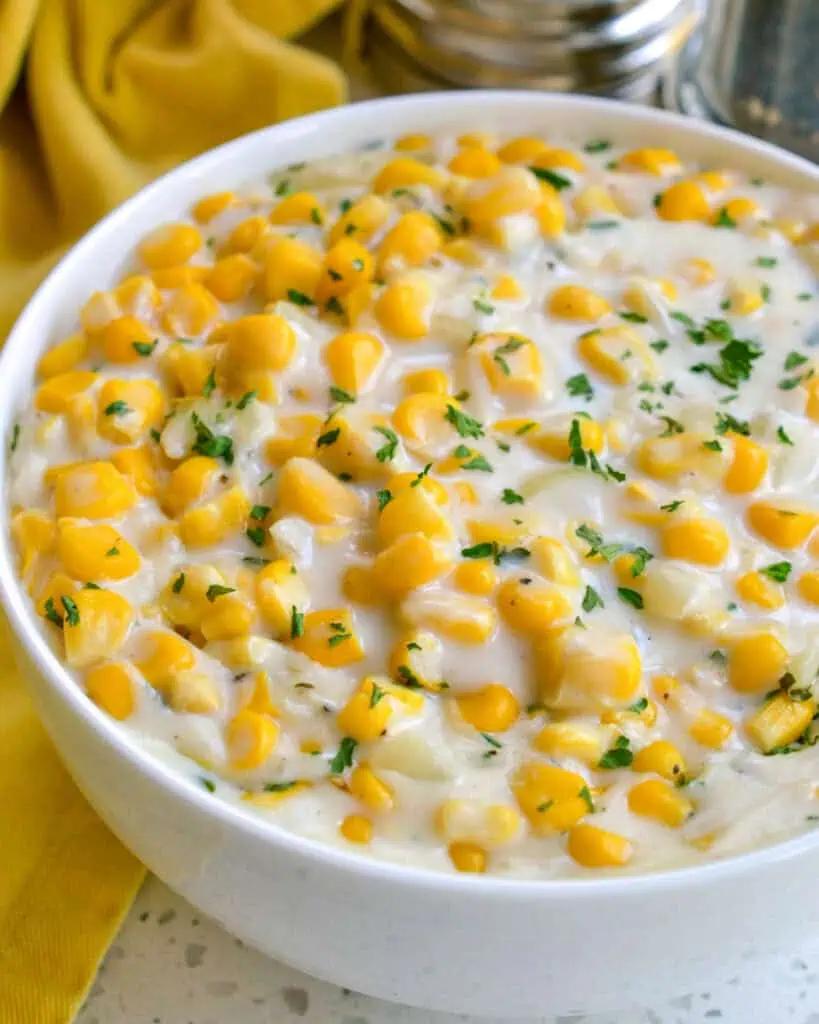 A bowl full of ceamed corn with chopped chives. 