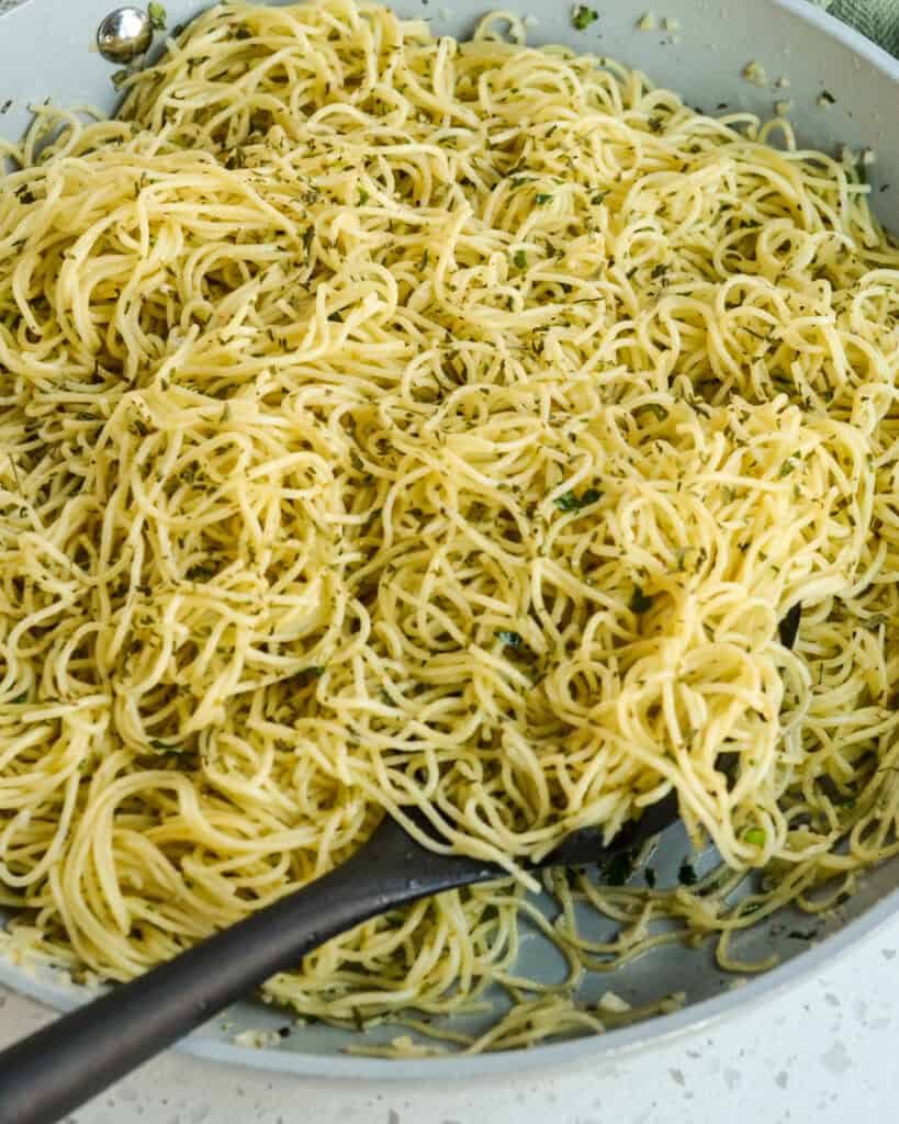 A skillet full of angel hair pasta with garlic, Parmesan cheese, and fresh herbs. 