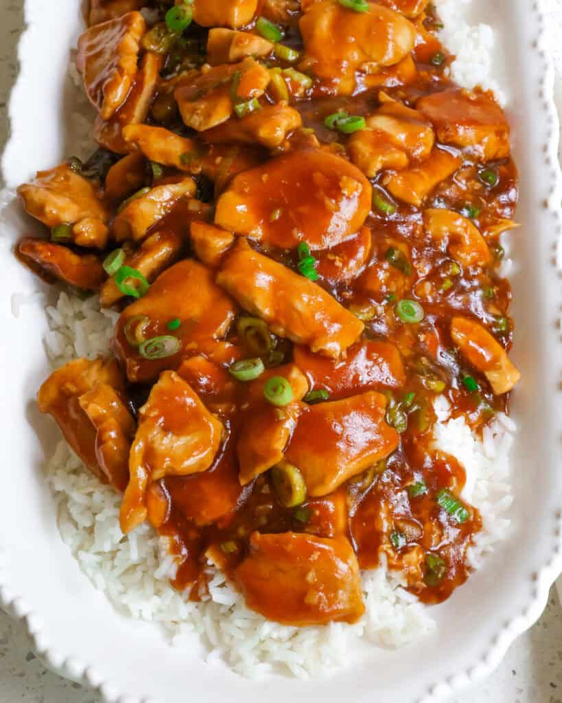 Bourbon chicken over rice on a serving platter. 