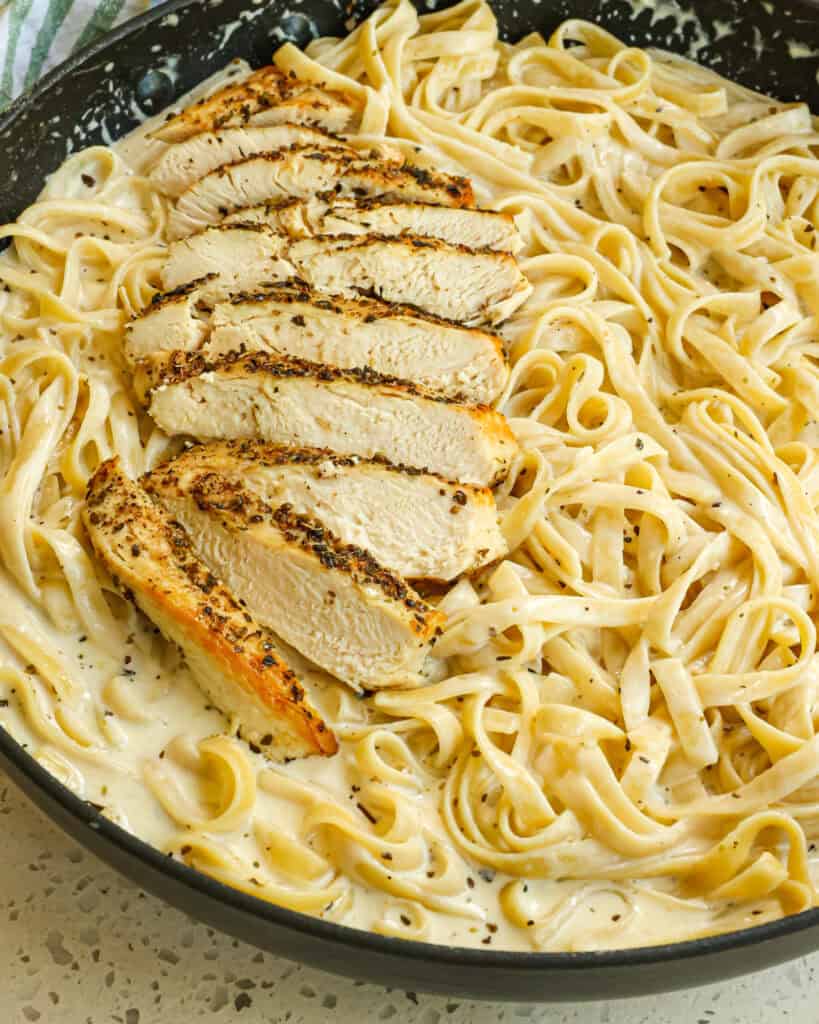 A large skillet full of fettucine chicken fettucine alfredo.