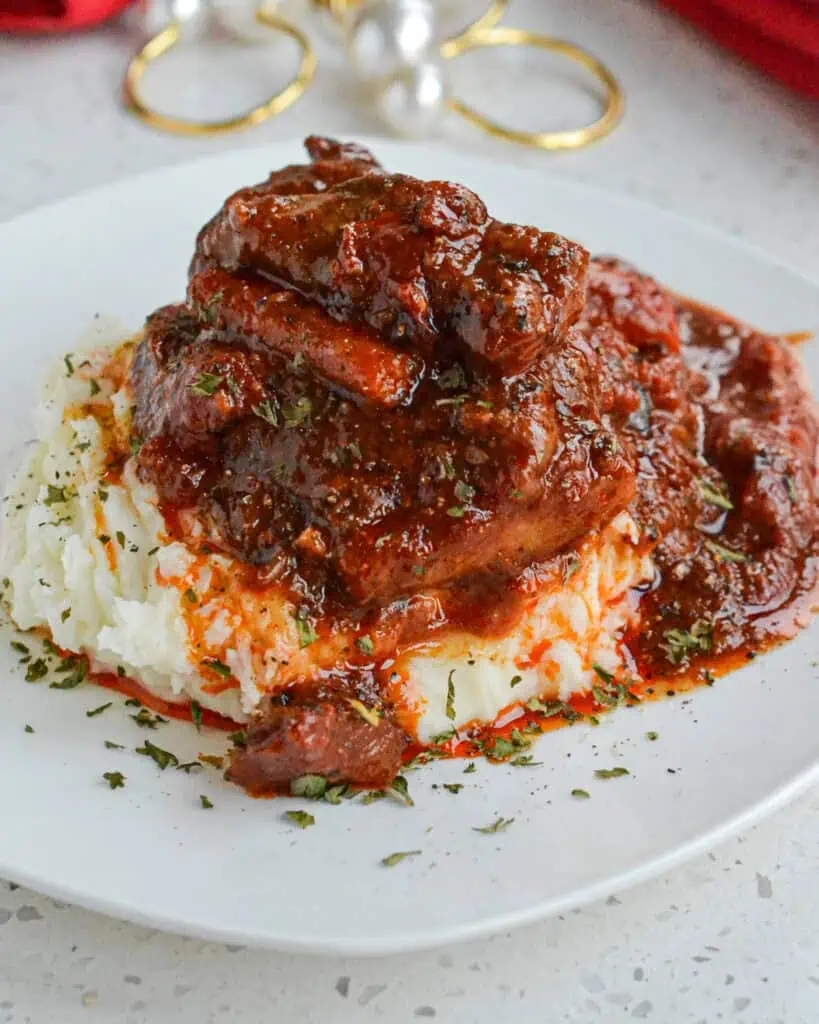 A serving of Swiss steak on a plate with napkins and napkin rings in the background. 