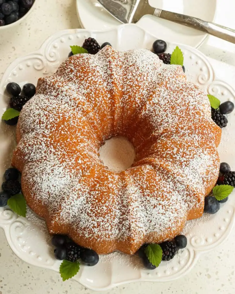 An overhead view of cream cheese pound cake dusted with powdered sugar and decorated with blackberries and blueberries. 