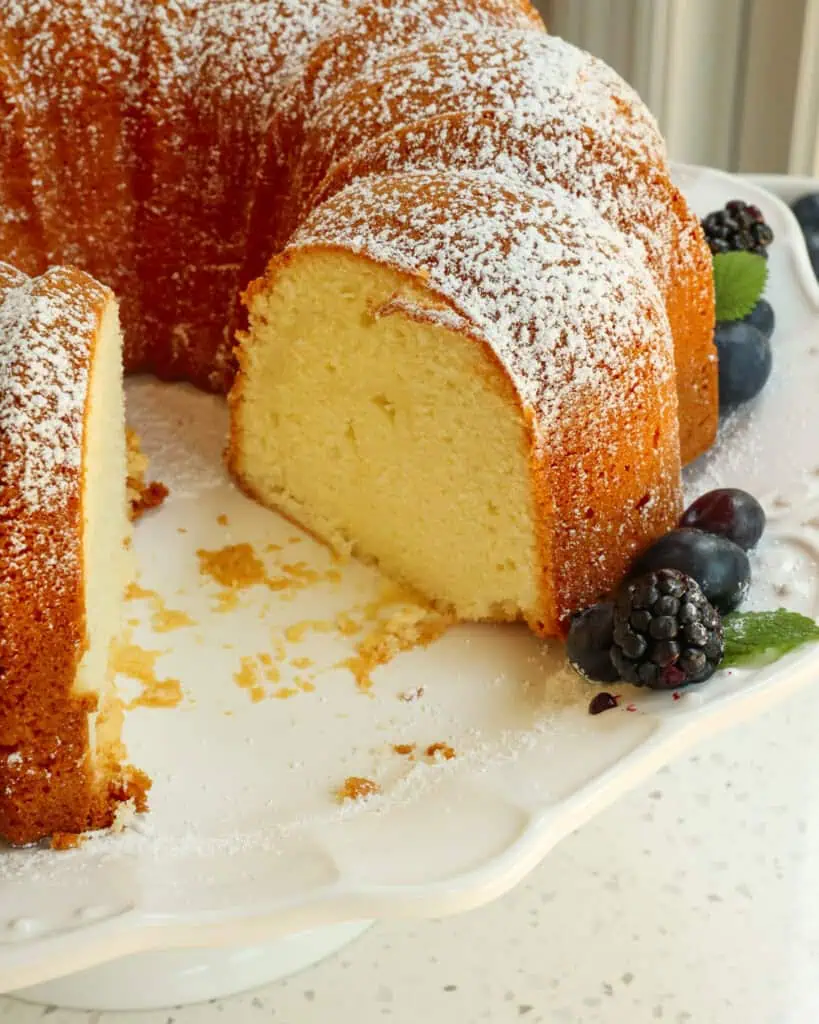 Cream cheese pound cake on a cake plate with a slice removed. 