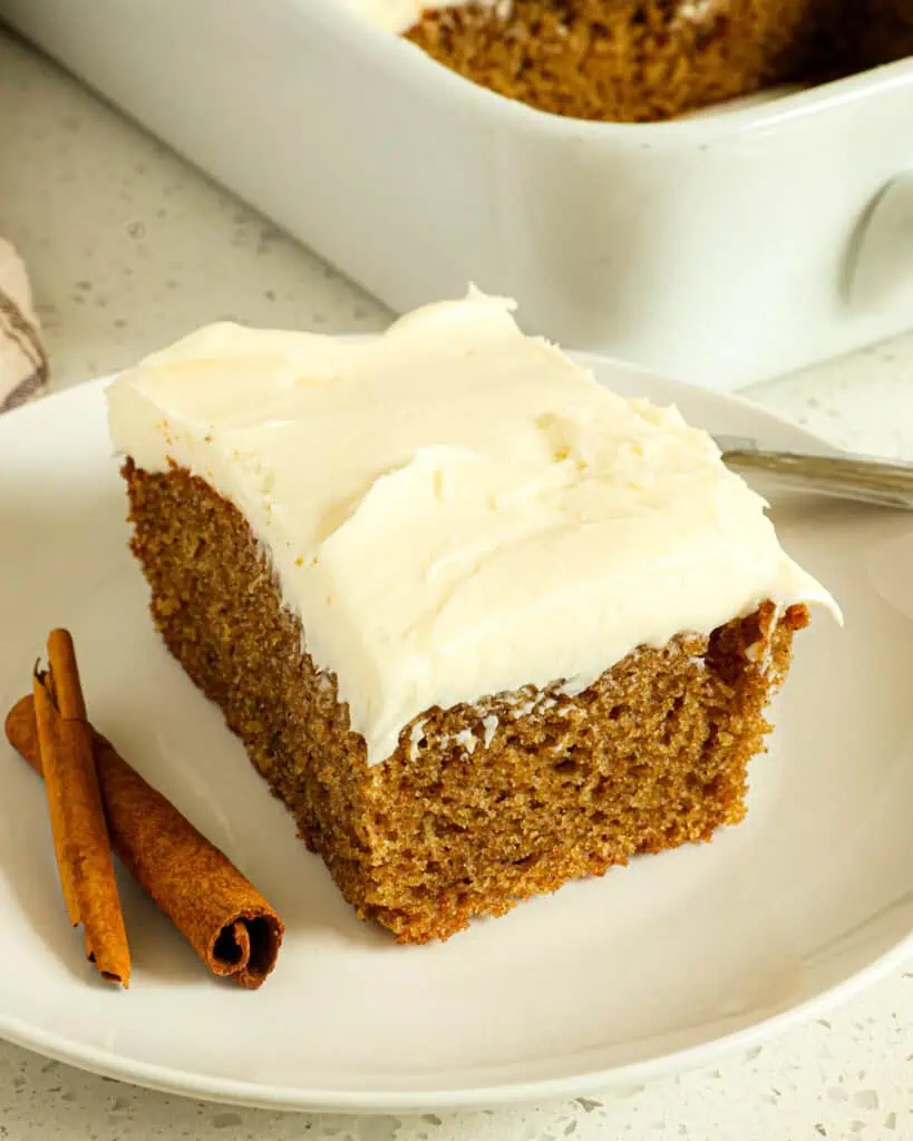 A piece of spice cake with cream cheese frosting on a plate with a fork.