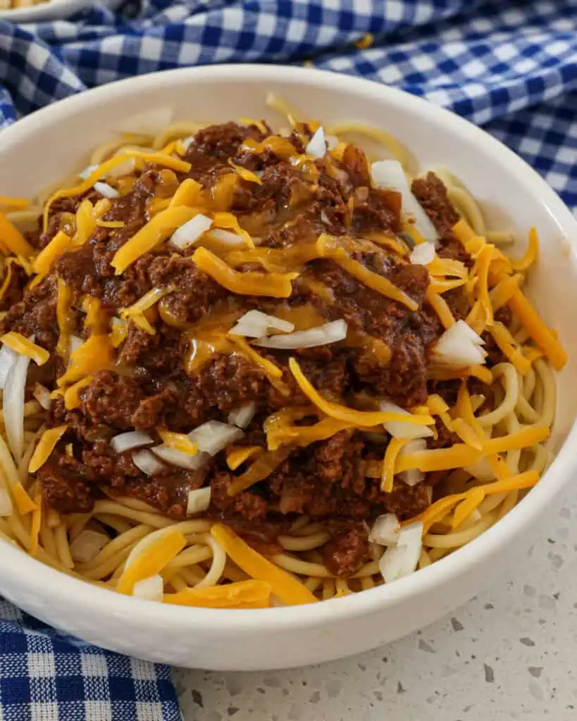 Cincinnati chili topped with cheddar and onions in a bowl. 