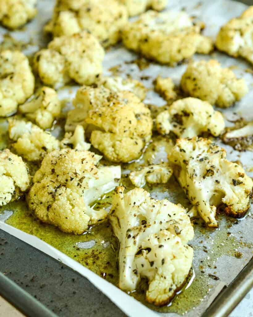 A baking covered with parchment paper and roasted cauliflower. 