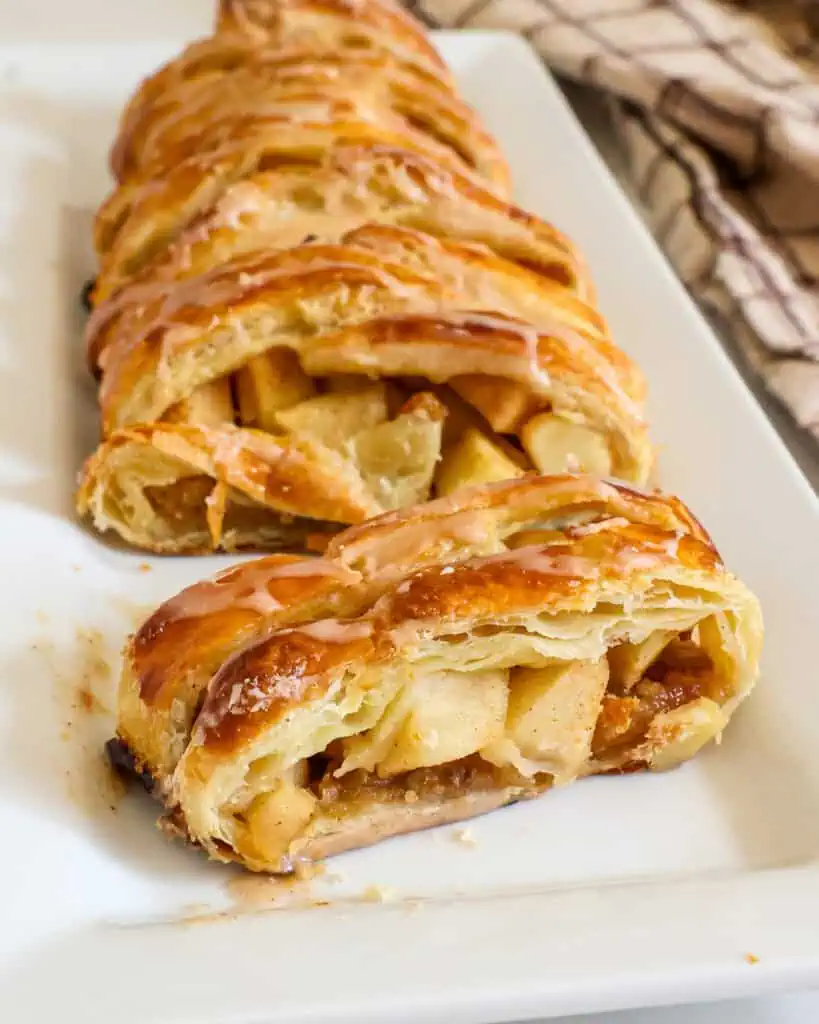 A sliced piece of apple strudel on a white platter. 