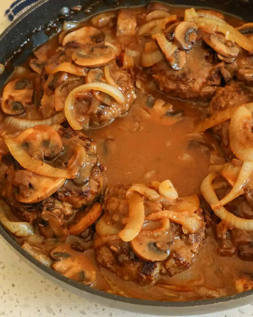 Hamburger Steak with an onion and mushroom gravy in a large skillet. 