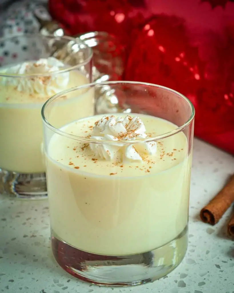 Two glasses of creamy eggnog. with whipped cream and a pinch of nutmeg. 