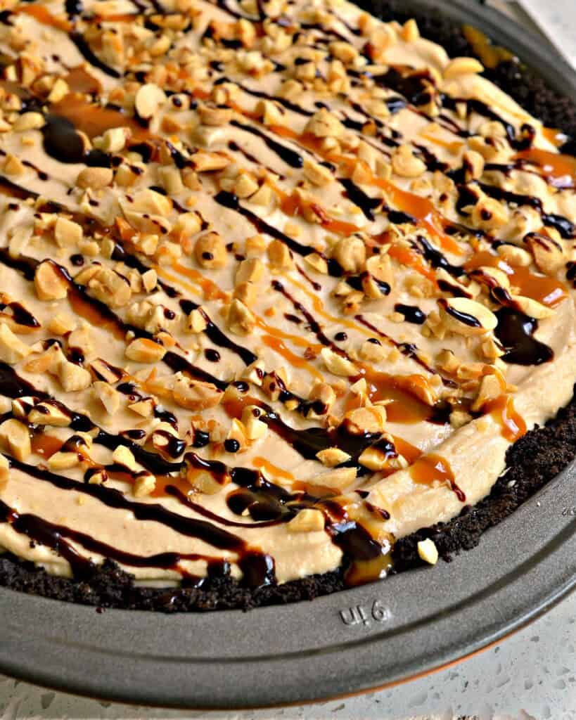 A close up view of peanut butter pie drizzled with caramel and chocolate sauce. 