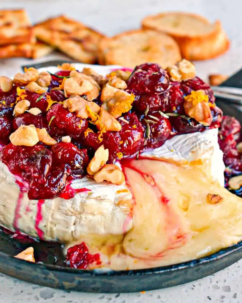 Baked brie with cranberries and walnuts, orange zest, and rosemary. 