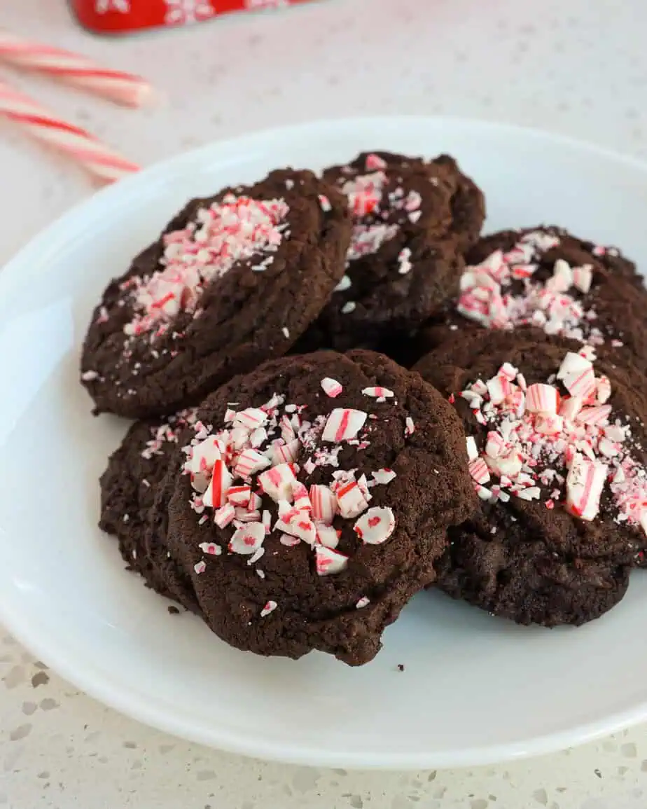 Chocolate peppermint cookies on a white seving plate with candy canes in the background. 