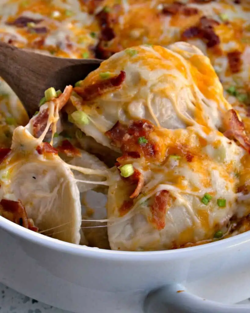 A close up view of pierogi casserole on a wooden spoon. 