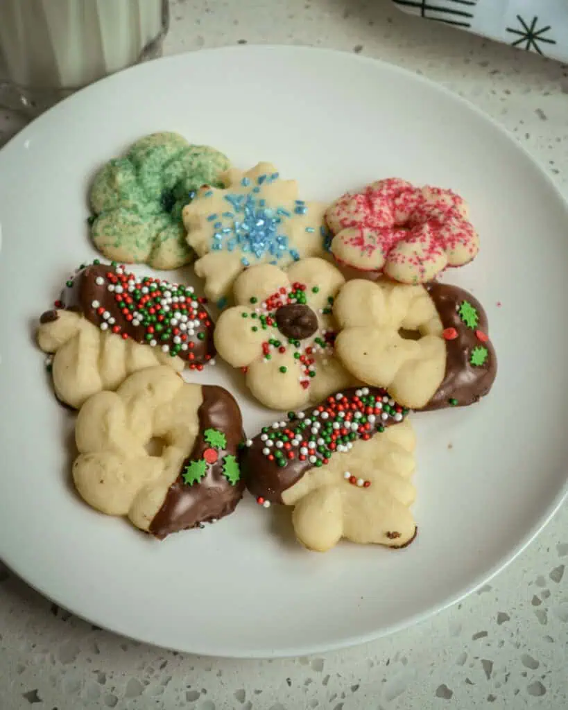 Spritz cookies on a plate with a glass of milk. 