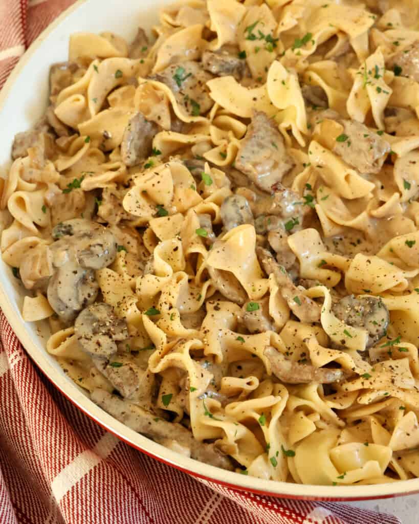 A large skillet full of beef stroganoff over noodles. 