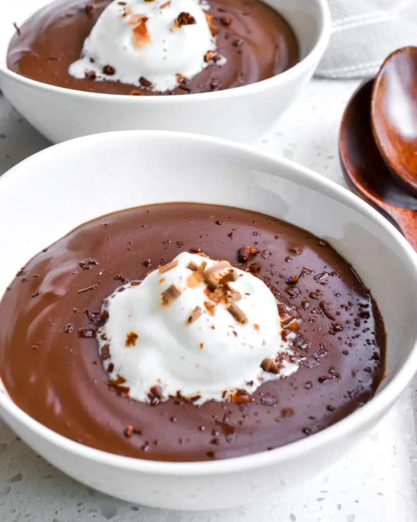 Chocolate pudding with whipped cream and chocolare shavings in a single serving bowl. 